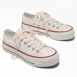 Vista dettagliata di sneaker platform low-top in tela crema con strisce rosse e nere