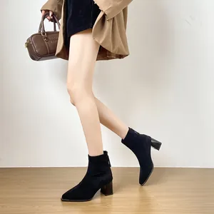 Schicke schwarze Wildleder-Stiefeletten mit Blockabsatz in einem stilvollen Outfit.