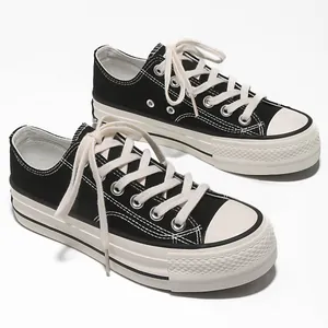 Primo piano di sneaker in tela nera low-top con plateau, lacci bianchi classici e suole spesse