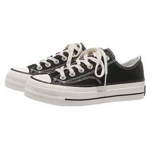 Sneaker platform basse in tela nera con suole spesse in gomma bianca e lacci bianchi