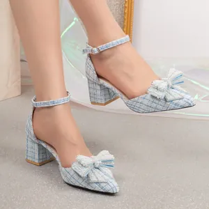 Close-up detail of light blue tweed chunky heels with pearl bow and ankle strap.