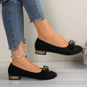Detail shot of black pointed-toe flat shoes with rhinestone bows and gold low heels.