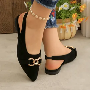 Close-up of elegant black suede pointed-toe flat mules featuring a gold chain buckle