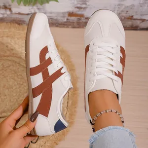 Close-up of stylish white and brown retro German training sneakers on model's feet.