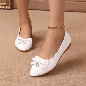 Detailed view of white leather pointed toe flats featuring a bow and gold ring decoration