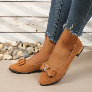 Detailed view of women's tan suede pointed-toe flat shoes with rhinestone bow decoration