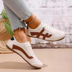 On-foot view of women's retro minimalist white sneakers with brown stripe detail