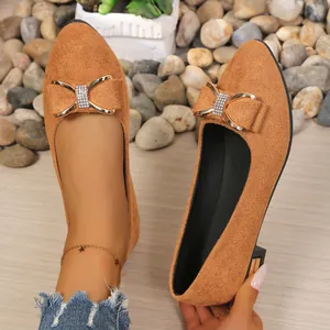 Close-up detail of stylish brown suede pointed toe flats with rhinestone bow ornament