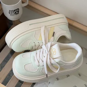 Detailed view of women's thick-sole sneakers in white, mint green and pastel yellow