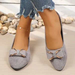 Detailed view of grey pointed-toe flat shoes with a sparkling rhinestone bow decoration