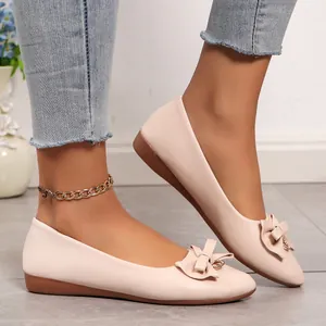 Elegant nude pink pointed-toe flat ballet shoes with bow accent shown on model foot