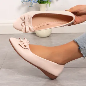 Close-up of pink pointed-toe ballet flats with bow and rhinestone detail on foot