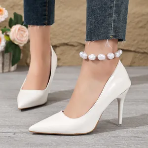 Elegant white pointed-toe stiletto high heels with decorative pearl anklet detail on model
