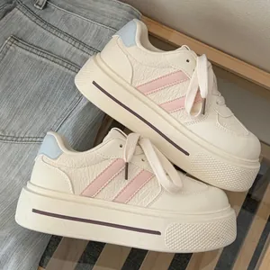 Detail view of stylish cream chunky platform sneakers with pink stripes and blue heel tabs