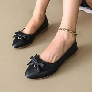 Detail showing the bow decoration and leather texture of black pointed flats.