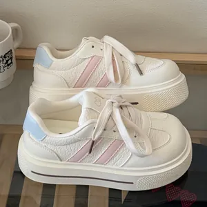 Side view of white platform sneakers with pink stripes and blue heel accents