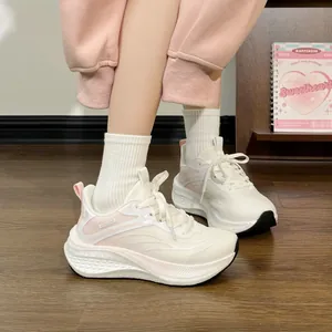Close-up detail of breathable cream and pink women's running shoes on wooden floor
