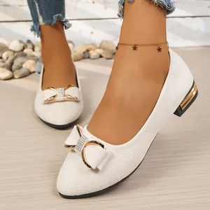Detail view of elegant cream pointed-toe flats with sparkling rhinestone bow decoration