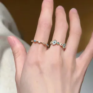 Detail view of two dainty adjustable gold rings with blue floral and gemstone accents