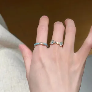 Close-up detail shot of elegant blue flower and enamel open rings on a female hand