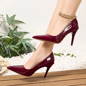 Detailed view of elegant glossy burgundy patent leather stiletto heels on pebble background