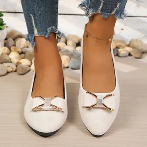 Close-up view of beige pointed-toe flats with sparkling rhinestone bow tie detail.