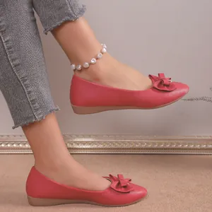 Close-up side view of red pointed-toe flat shoes featuring an elegant bow detail decoration