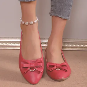 Detailed macro view of red pointed toe flats featuring elegant bow and rhinestone detail.