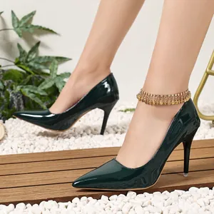 Elegant dark green glossy pointed-toe stiletto pumps shown on model in a garden setting.