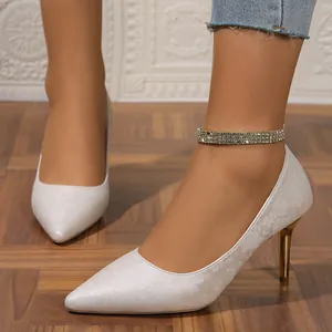 Elegant detail shot of white floral pumps with gold stiletto heels worn by a model