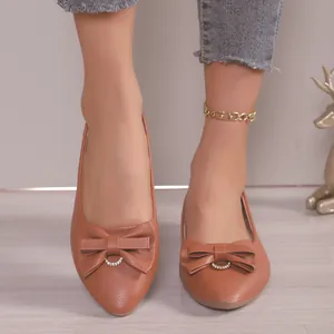 Detailed view of brown pointed toe flats for women with bow and rhinestone decor