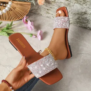 Detail shot of elegant flat slide sandals adorned with pearls and shiny rhinestones.