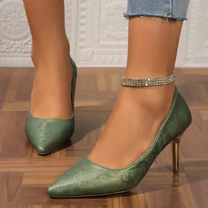 Elegant green floral print stiletto heels with gold heel detail on a model's feet.