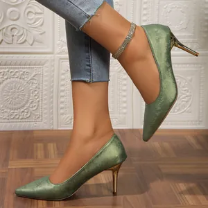 Close-up of elegant green pointed-toe pumps with floral jacquard and gold heel