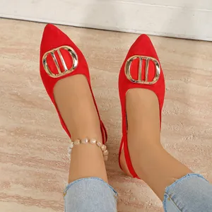 Détail de ballerines rouges à bout pointu et boucle dorée portées aux pieds.