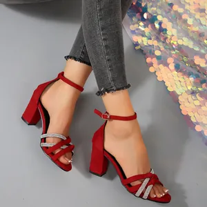 Détail de sandales rouges en daim à talon bloc avec brides à strass étincelants.