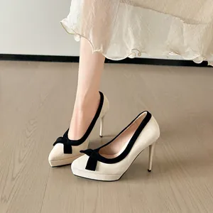 Elegante beige pumps met spitse neus, zwarte strik en een hoge plateauzool
