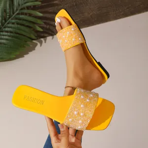 Close-up of yellow slide sandals with elegant pearl and rhinestone embellishments
