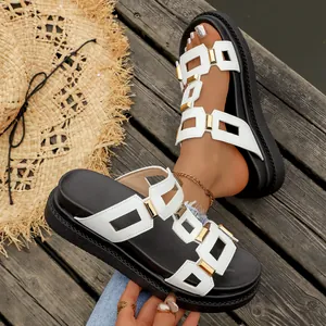 Détail de sandales à plateforme avec boucles dorées et lanières blanches élégantes.