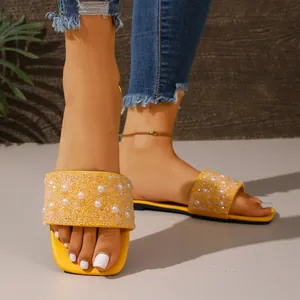 Detailed view of yellow summer flat sandals with pearls and glittering rhinestones
