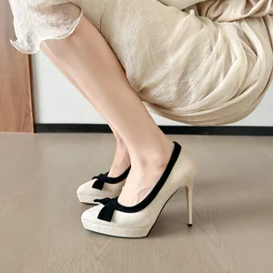Close-up van beige plateauhakken met een elegante zwarte strik en een puntige neus