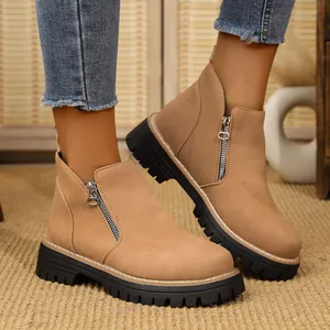 Close-up of stylish tan suede women's ankle boots featuring side zippers and thick black lug soles