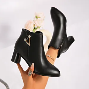 Close-up of black chunky heel ankle boots with gold V-shaped rhinestone buckle detail