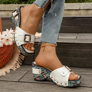 Detailopname van witte retro sleehak sandalen met gesp en kleurrijk geweven platform op hout.