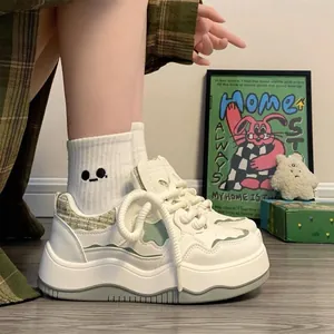 Close-up of stylish white platform sneakers with green wave accents and tweed details