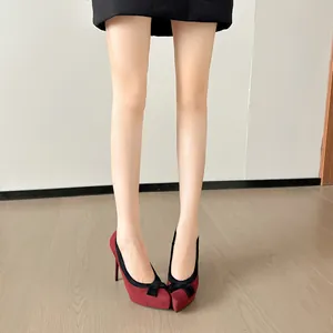 Detailweergave van elegante bordeauxrode suède pumps met een zwarte strikaccent