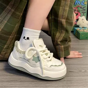 Detailed view of thick-soled white sneakers with green star patterns on a model's foot