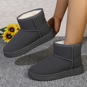 Primer plano de botas de nieve gris oscuro cálidas con forro de piel sintética blanca.