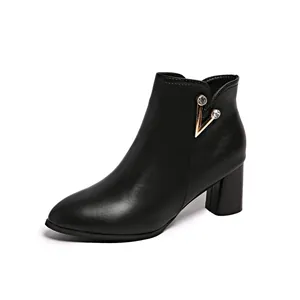 Side view of black leather ankle boots with gold rhinestone V-ornament and block heel