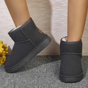 Primer plano de botas de nieve grises planas para mujer con forro de piel blanca cálida.